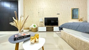 A modern bedroom with a large bed, a flat-screen TV, and a small table with a book and candles.