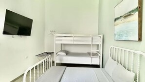Ein Zimmer mit Etagenbett, Deckenventilator, Flachbildfernseher und einem Wandbild.