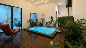 A swimming pool with a wooden deck, surrounded by plants and a chair. - House with private pool and fully equipped BBQ (Jaco)