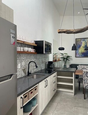 A modern kitchen with a built-in microwave, a coffee machine, and a hanging light fixture. - House with private pool and fully equipped BBQ (Jaco)