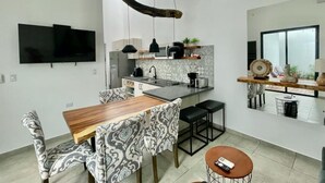 A modern kitchen with a wooden dining table, patterned chairs, and a hanging light fixture. - House with private pool and fully equipped BBQ (Jaco)