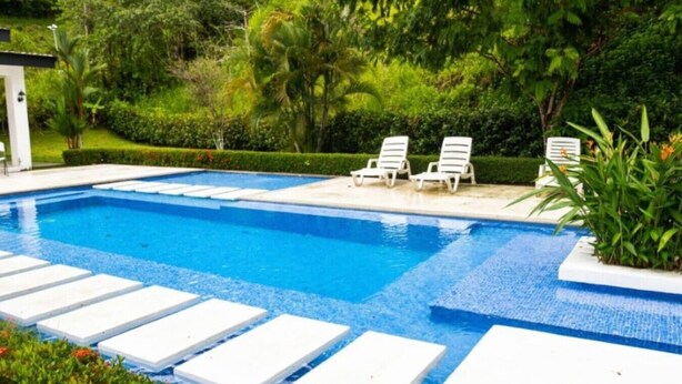 A swimming pool with white lounge chairs and a paved deck. - House with private pool and fully equipped BBQ (Jaco)