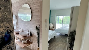 Un dormitorio moderno con una cama grande, una mesita de noche y una ventana con vistas a zonas verdes.