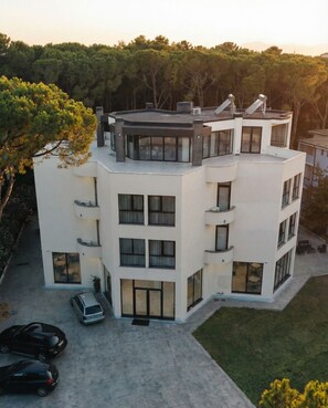 A modern multi-story building with a flat roof, large windows, and a carport.