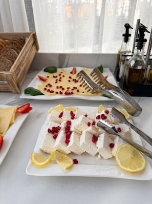 A table with a cheese platter, lemon slices, and pomegranate seeds.