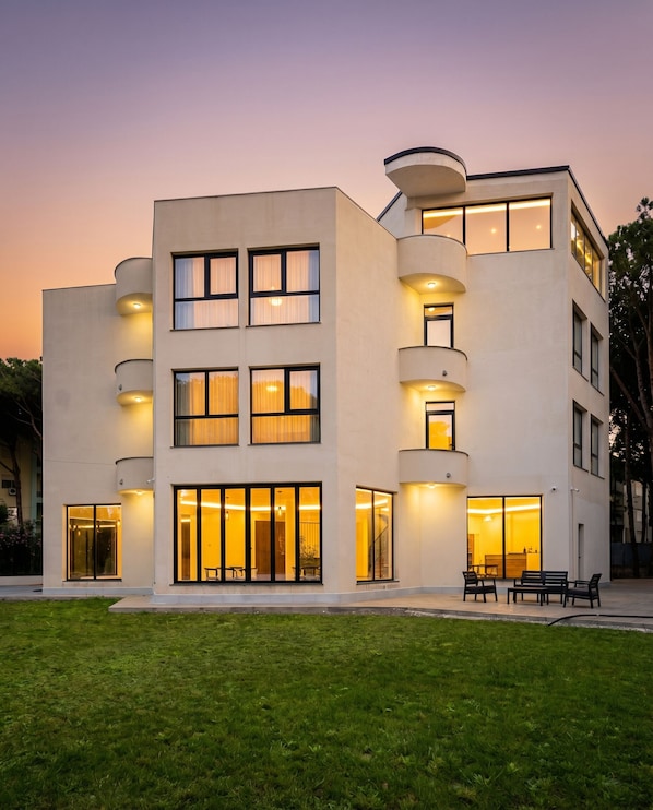 A modern multi-story building with balconies, large windows, and outdoor seating.