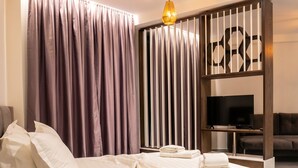 Een moderne hotelkamer met een bed, een televisie en een houten scheidingswand.