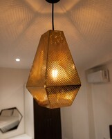 Una lámpara colgante de diseño geométrico con un patrón de metal perforado.