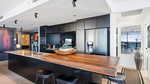 A modern kitchen with a large island, bar stools, and built-in appliances.