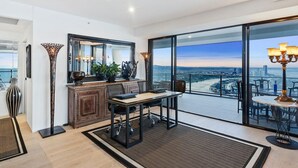 A modern living room with a large window, a dining area, and a view of a cityscape.