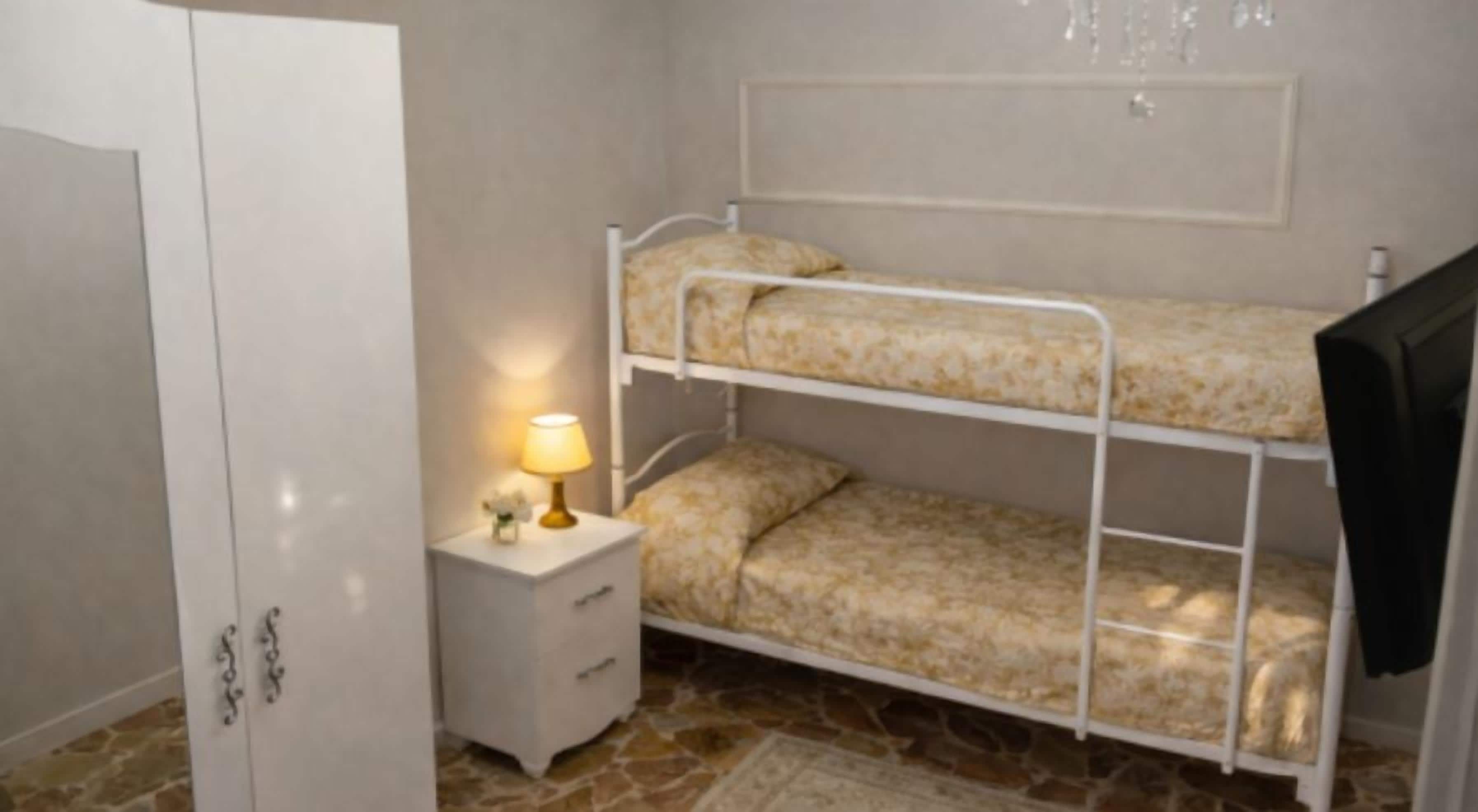 A bunk bed with a patterned mattress, a bedside table with a lamp, and a wardrobe.