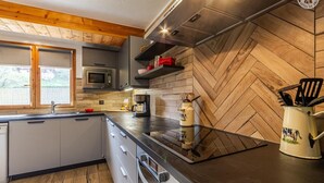 Eine moderne Küche mit Wandsäbel aus Holz, Edelstahlgeräten und einem Fenster mit Blick.