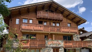 Eine Holzhütte mit Natursteinfassade, Balkonen mit Holzgeländern und einem Schild mit der Aufschrift "LE SABOIA".
