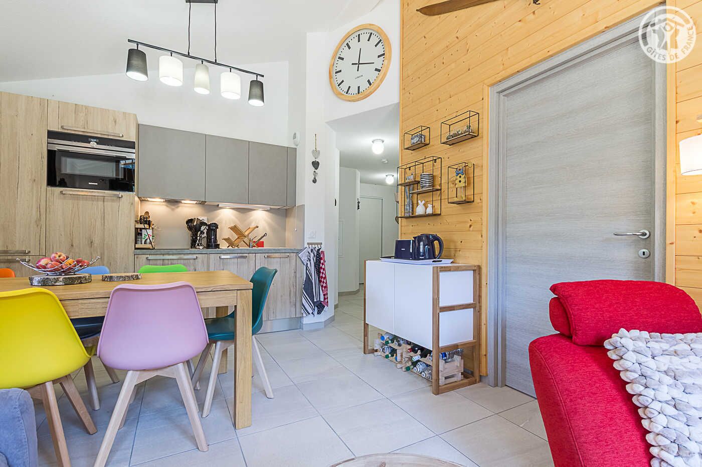 Une cuisine moderne avec un coin repas, un canapé rouge et une porte en bois.