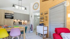 Une cuisine moderne avec un coin repas, un canapé rouge et une porte en bois.
