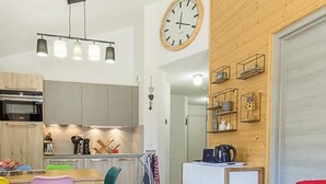 Une cuisine moderne avec un coin repas, une table ronde en bois et un canapé rouge.