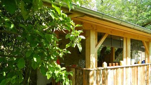 Una struttura in legno con un portico coperto, gradini in pietra e una finestra che si affaccia sul verde.