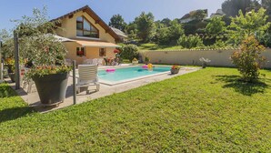 Una casa con piscina, césped y jardín con plantas en macetas.