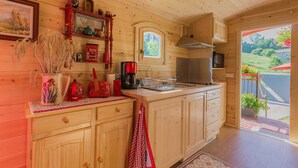 Cocina de cabaña de madera con cafetera, hervidor y ventana con vista a un jardín.