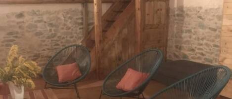 A rustic interior with wooden furniture, stone walls, and a staircase.