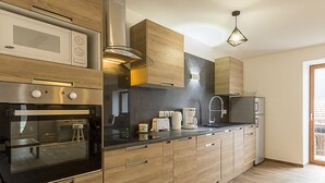 A modern kitchen with wooden cabinets, stainless steel appliances, and a black countertop.