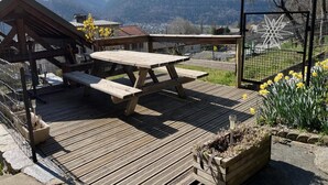 A wooden deck with picnic tables overlooking a mountainous landscape.