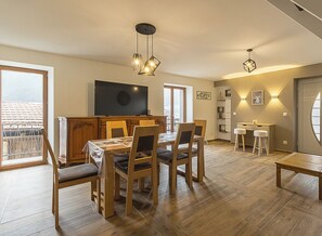 Un soggiorno moderno con zona pranzo, mobili in legno e televisore a parete.