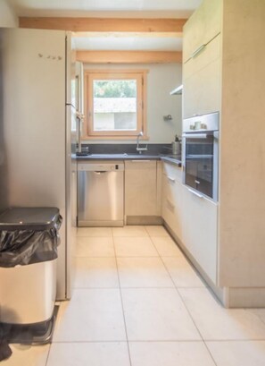 Una cocina funcional con electrodomésticos de acero inoxidable, una ventana y piso de baldosas.