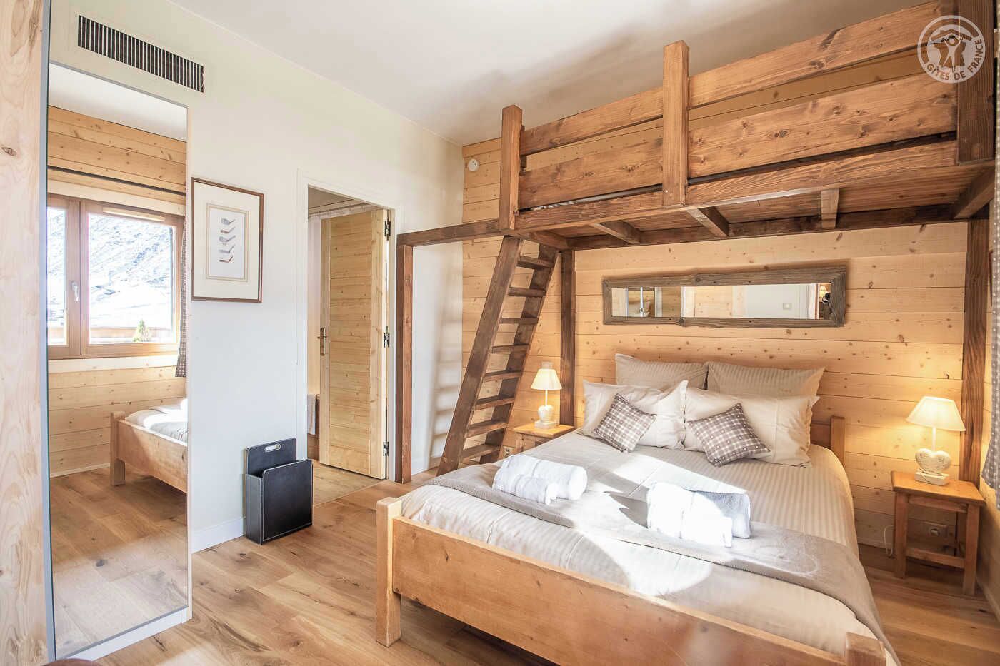 Une chambre avec un plafond en bois, un lit avec des oreillers, une table de chevet avec une lampe et une fenêtre donnant sur l’extérieur.