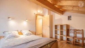 A bedroom with a wooden bed, a wardrobe, and a door leading to another room. - LE Chenavelle D'en Haut (HAUTELUCE LES SAISIES)