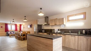 A modern kitchen with wooden cabinets, a central island, and pendant lighting. - LE Chenavelle D'en Haut (HAUTELUCE LES SAISIES)