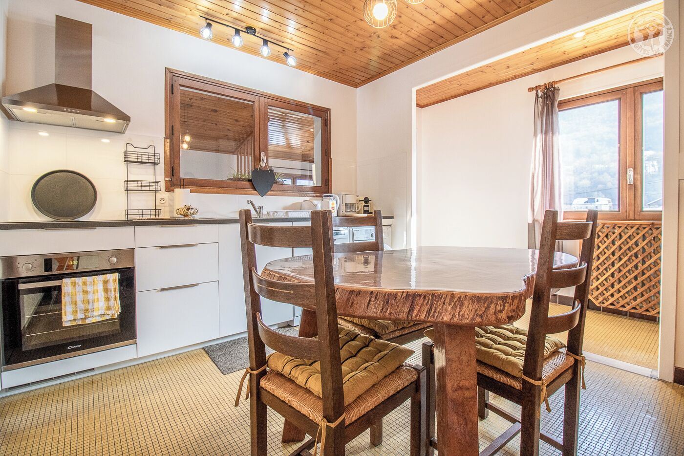 A kitchen with a round wooden table and chairs, a stove, and a large mirror above the sink.