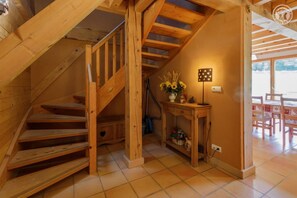 Staircase leads to an upper level, with a console table and vase of sunflowers below.