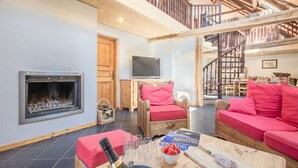 A cozy living room with a fireplace, wooden furniture, and a staircase leading to an upper level. - Chez LE Marquis DU Pontet 5 (VALLOIRE)