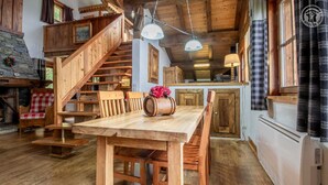 A rustic wooden interior with a dining table, chairs, a staircase, and a kitchen area. - Chalet Bellacomba-grd Paradis (SAINTE FOY TARENTAISE)