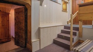 Eine Holztreppe führt zu einer Empore mit einer Bank und einem kleinen Tisch.