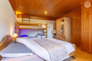 Ein Schlafraum mit Etagenbetten, Holzboden und Nachttischlampe, sowie einem Kleiderschrank.