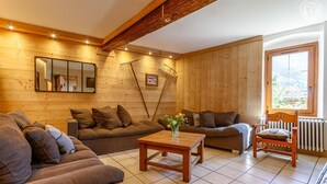 Ein gemütliches Wohnzimmer mit Holzwänden, einer Couch, einem Sessel und einem Tisch mit Blumen.