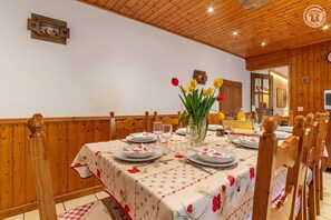 Ein Essbereich mit einem Holztisch, gedeckt für vier Personen, umgeben von Holzstühlen mit gepolsterten Sitzflächen.