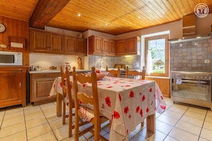 Una cocina con armarios de madera, una mesa de comedor con mantel floral y un horno grande.