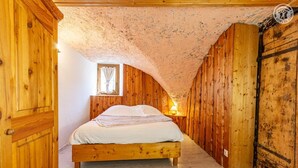 Ein Zimmer mit Holzboden, einem Bett, einem Fenster und einer Lampe.