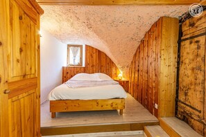 Una habitación de madera con una cama, una ventana y una lámpara.