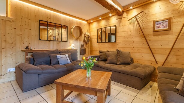 Ein gemütliches Holzinterieur mit einer Sofagarnitur, einem Holztisch und einem Spiegel.
