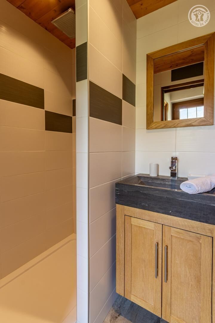 A bathroom with tiled walls, a wooden vanity, a mirror, and a towel.