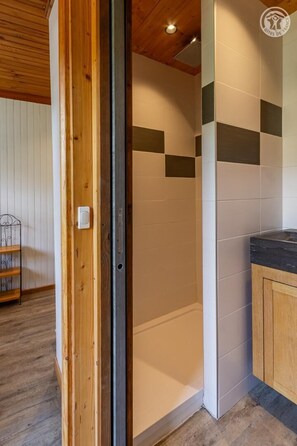 Ein Badezimmer mit Dusche, Holzboden und gefliesten Wänden.