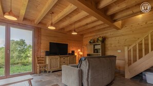 A wooden interior with a sofa, a television, and a staircase. - LE Chalet DE LA Source (MONTAGNOLE)
