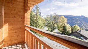 Een houten balkon met uitzicht op bomen en bergen.