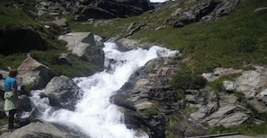Une cascade dans un paysage rocheux, avec une personne debout à proximité.