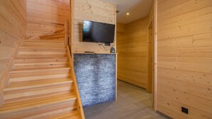 Un interior de madera con una escalera, un televisor de pantalla plana en la pared y una pared de acento de piedra.