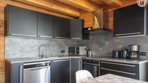 Una cocina moderna con armarios oscuros, electrodomésticos de acero inoxidable y techo de madera.